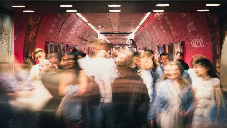 Blurred image capturing people walking through a tunnel.